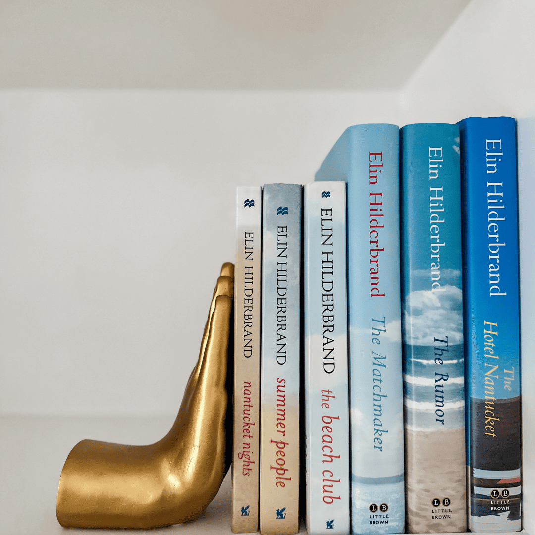 six elin hilderbrand books on bookshelf with bookend