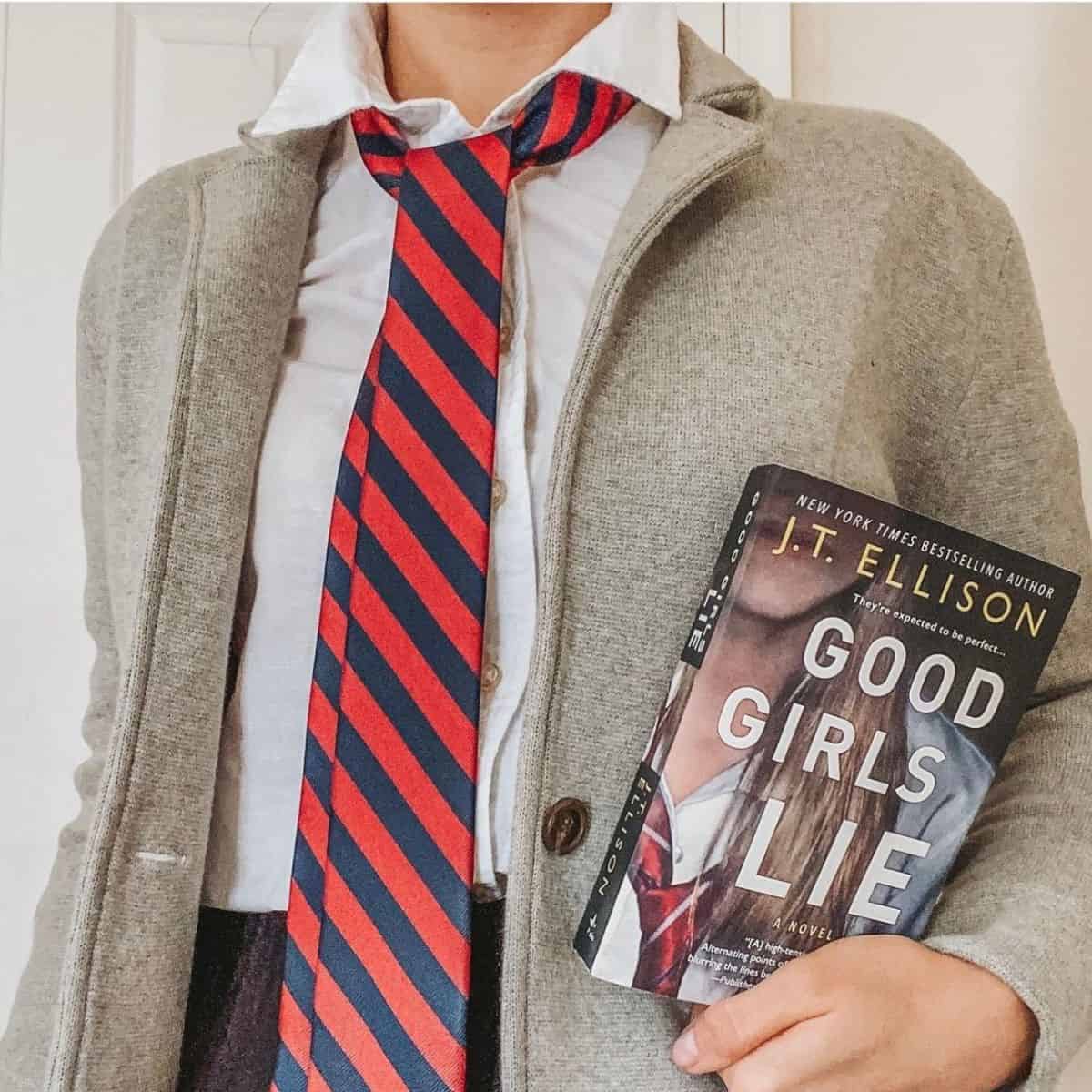 woman holding good girls lie by jt ellison and wearing clothes that match the cover.