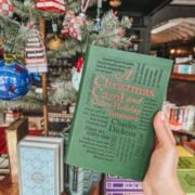 a christmas carol by charles dickens in front of a christmas tree.