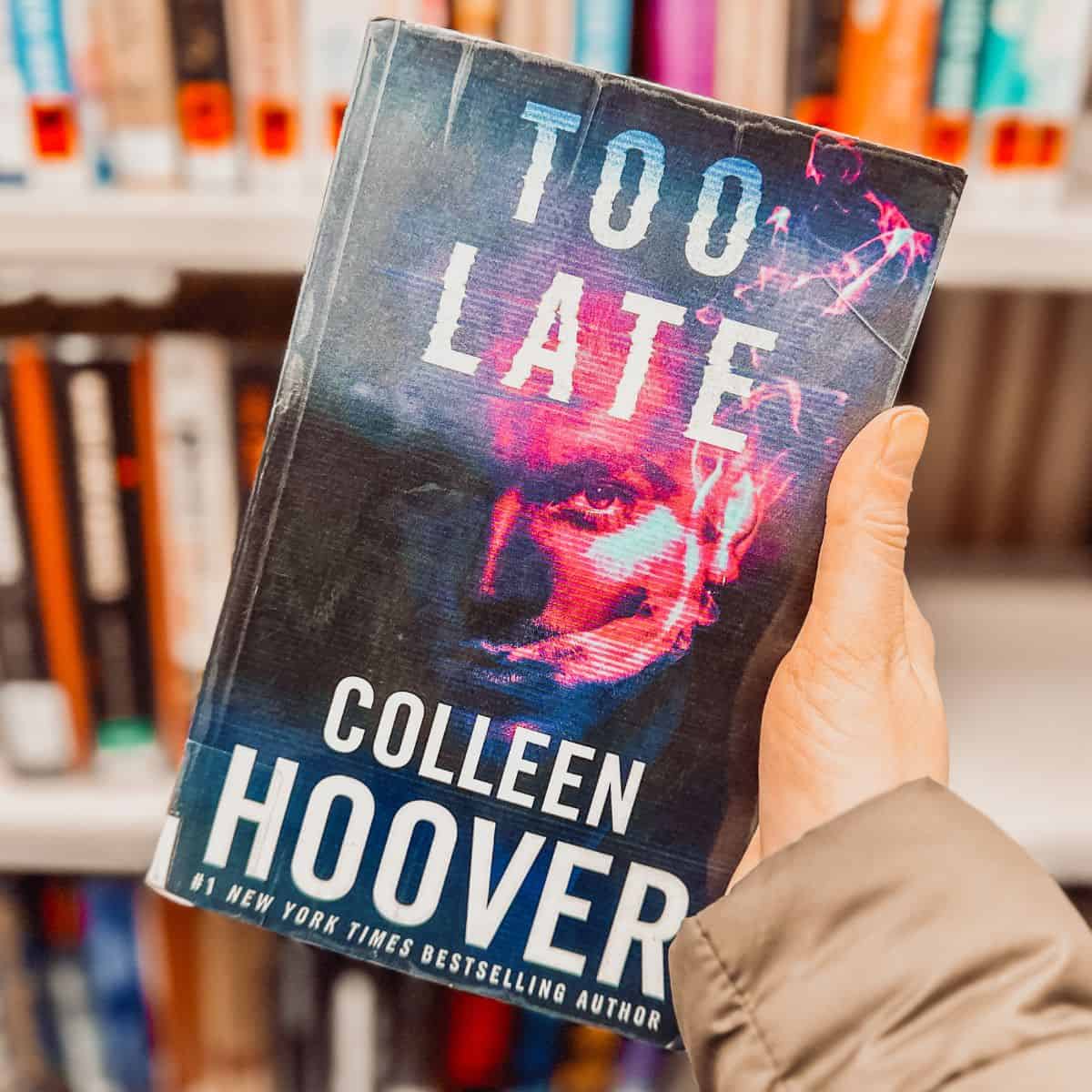 too late by colleen hoover in front of bookshelves.