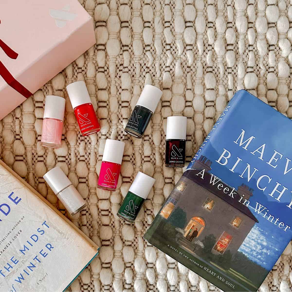 olive and june winter 2024 nail polish collection with books on a rug.