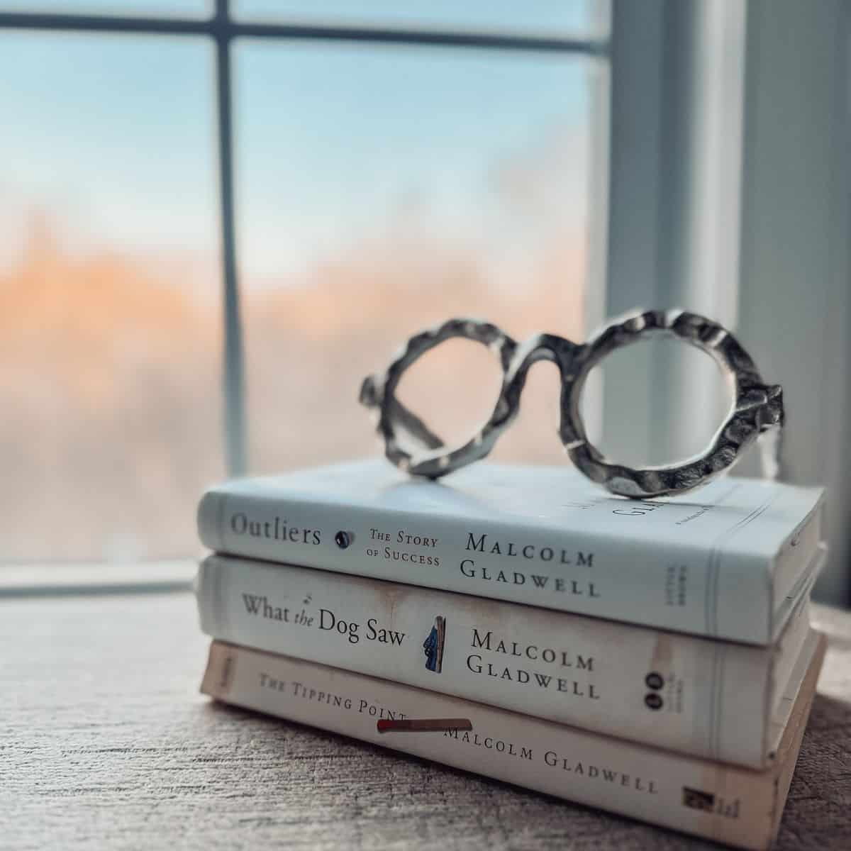 stack of malcolm gladwell books with glasses on top.