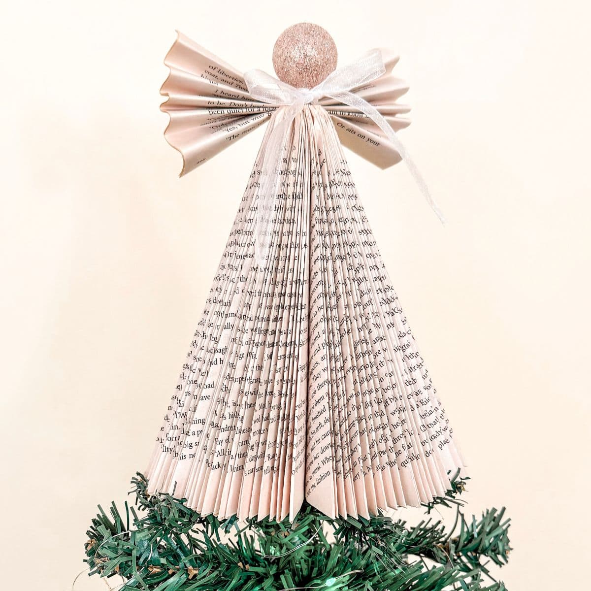 DIY folded book page Angel Christmas tree topper on a tree.