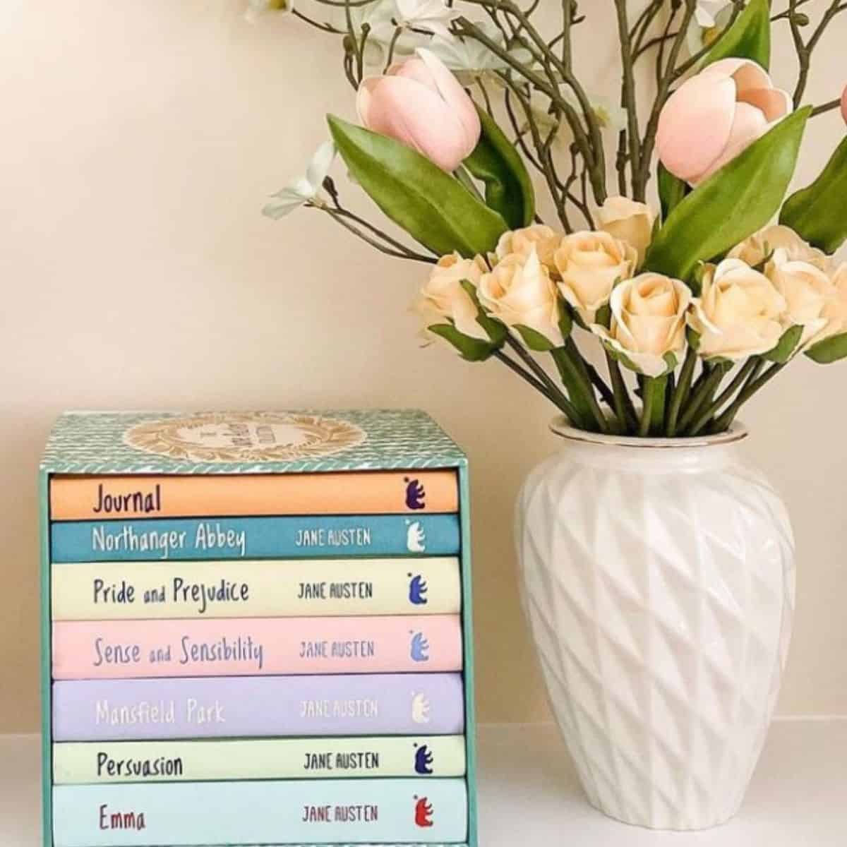 jane austen book set with a vase of flowers.