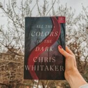 All the colors of the Dark by Chris Whitaker in front of trees.