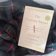 The Tipping Point by Malcolm Gladwell next to a plaid blanket.