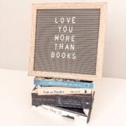 "love you more than books" on a letter board with a stack of romance books.