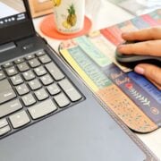 woman's hand on a mousepad next to a laptop.