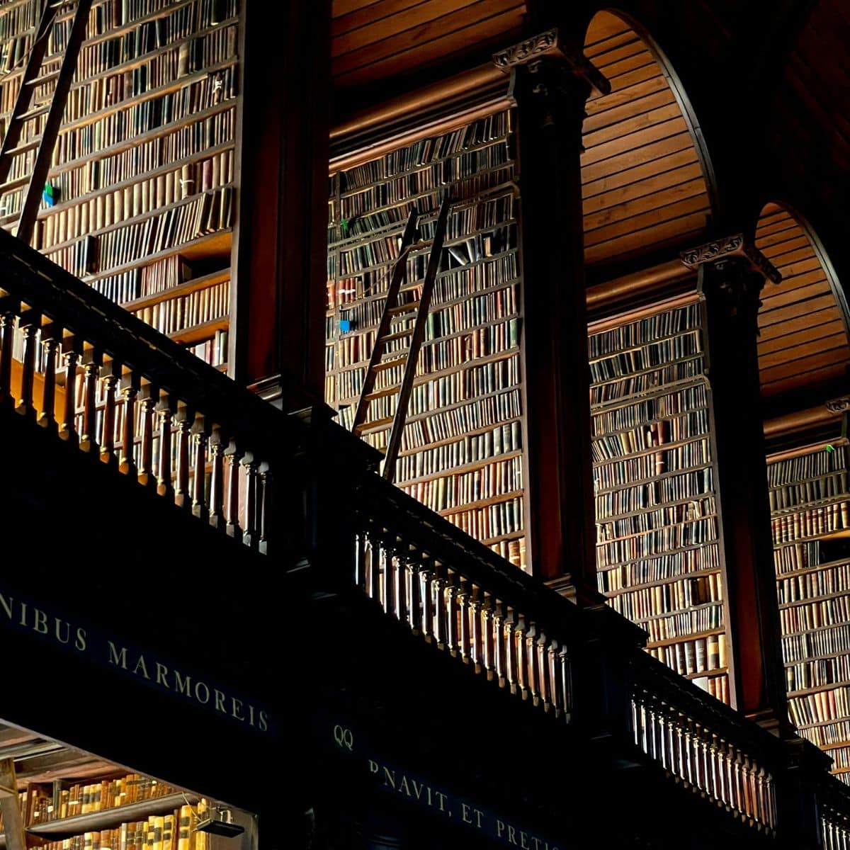 rows of bookshelves and a book ladder in the trinity college library.